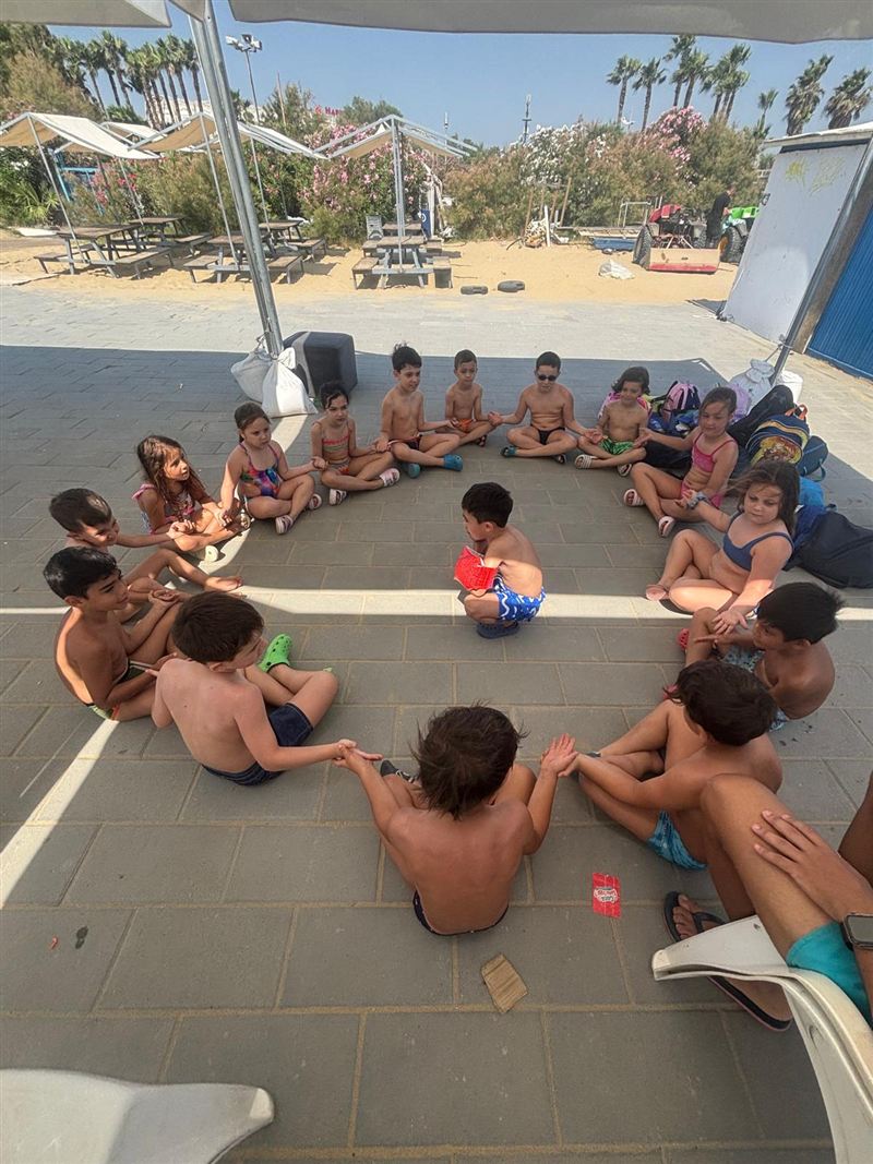 Bambini seduti in cerchio durante un momento di vita di gruppo al Summer Village