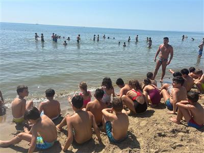 Bambini seduti sulla riva del mare con l'educatore