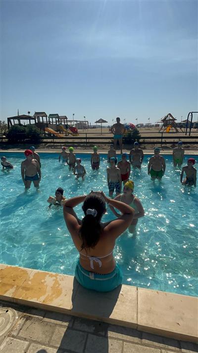 Bambini in piscina con cappellini colorati durante la lezione