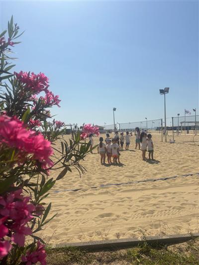 Bambini in spiaggia con gli oleandri rosa in primo piano